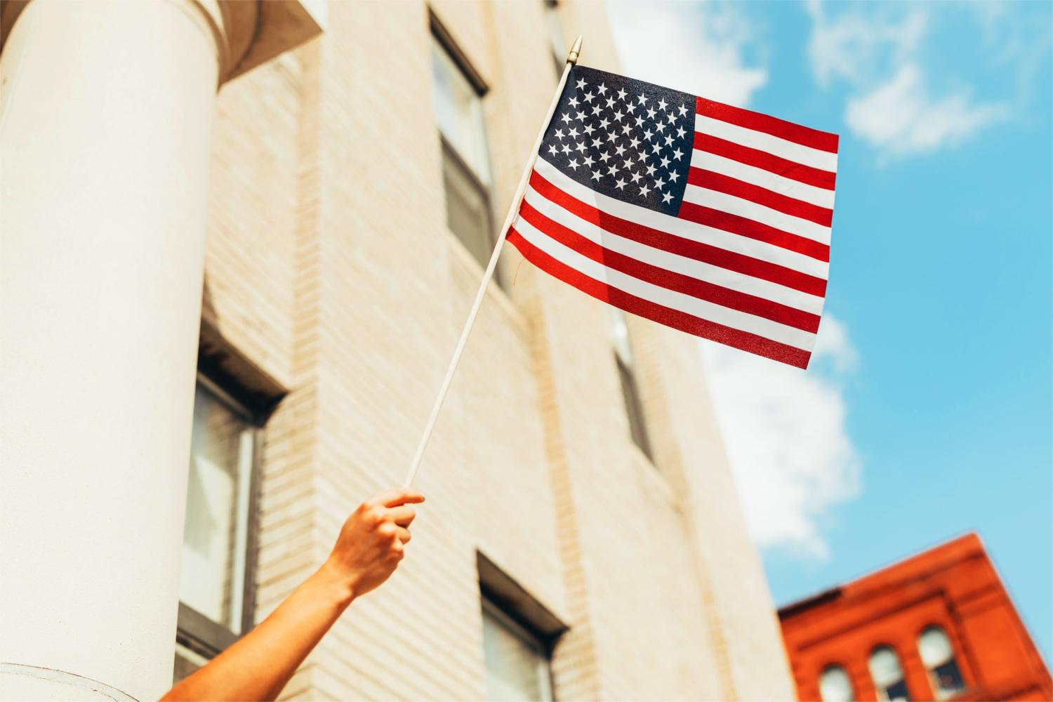 Person holding American flag out of the window